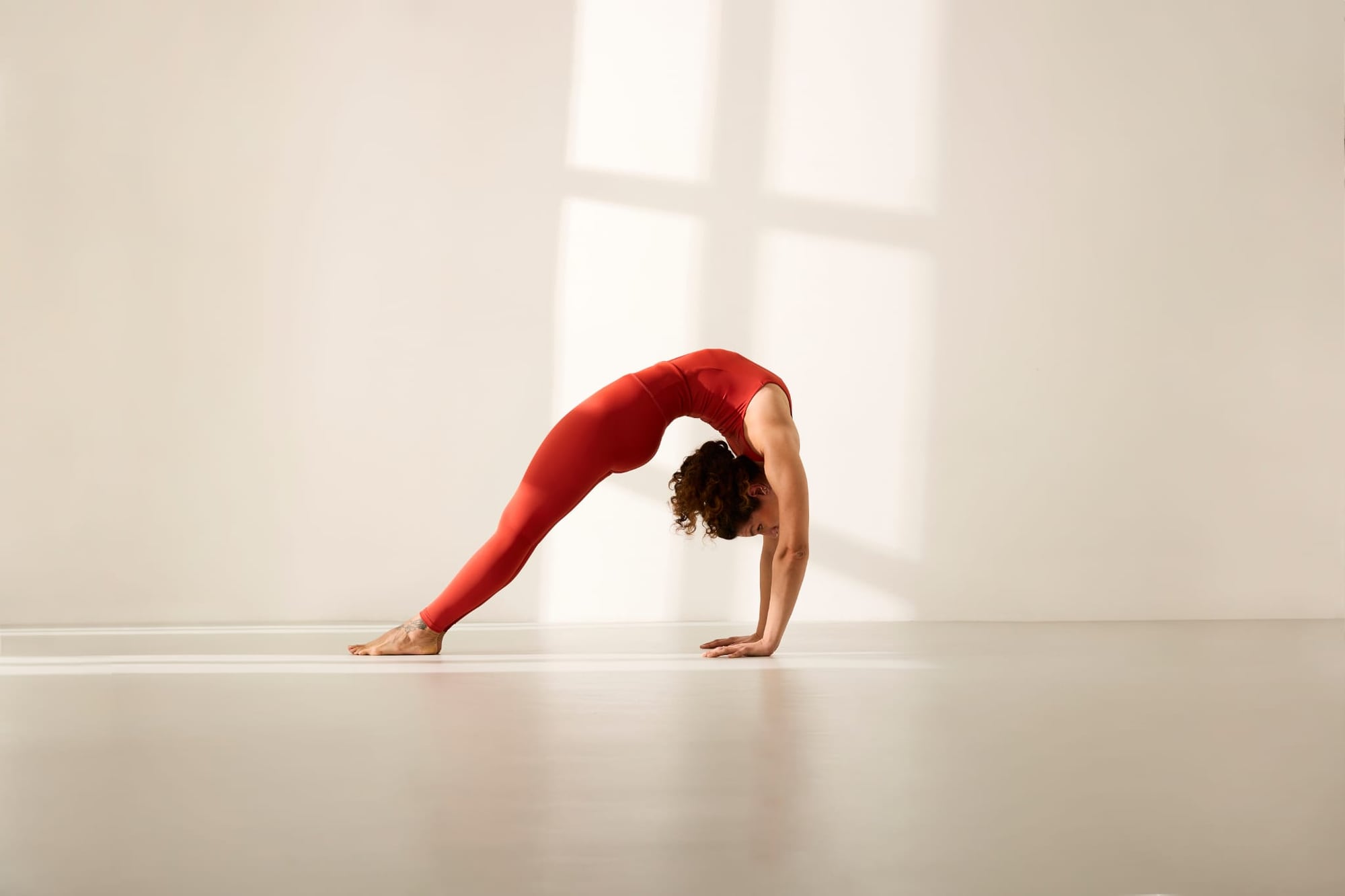 Giulia in una pratica dinamica di yoga, studio inondato di luce naturale.